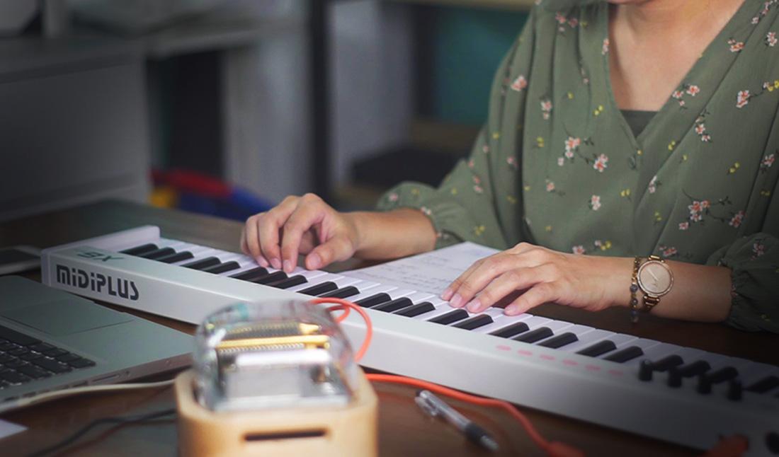 編曲師在MIDI鍵盤上彈奏旋律幫智慧音樂盒的客戶製作客製化曲目