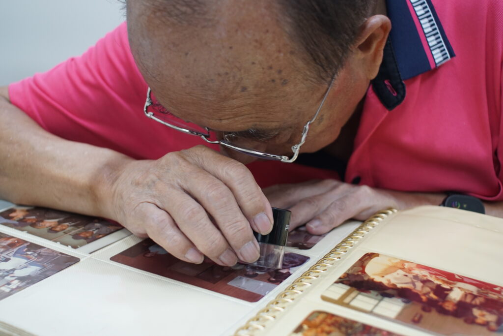 黃龍溪總經理在協櫻音樂鈴博物館內，使用放大鏡仔細觀看老照片的細節。