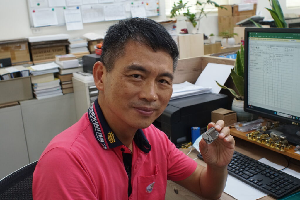 張錦財先生手持他親手設計的迷你音樂鈴機芯。