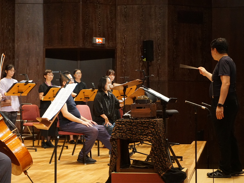 Taiwanese composer Chun-Yen Chang at the National Concert Hall, Taiwan. He is conducting intently, with a Muro Box-N40 Sublime smart music box placed in front of him, and a professional vocal chamber ensemble (Mysterium Musicum) during a rehearsal recording before a joint performance.